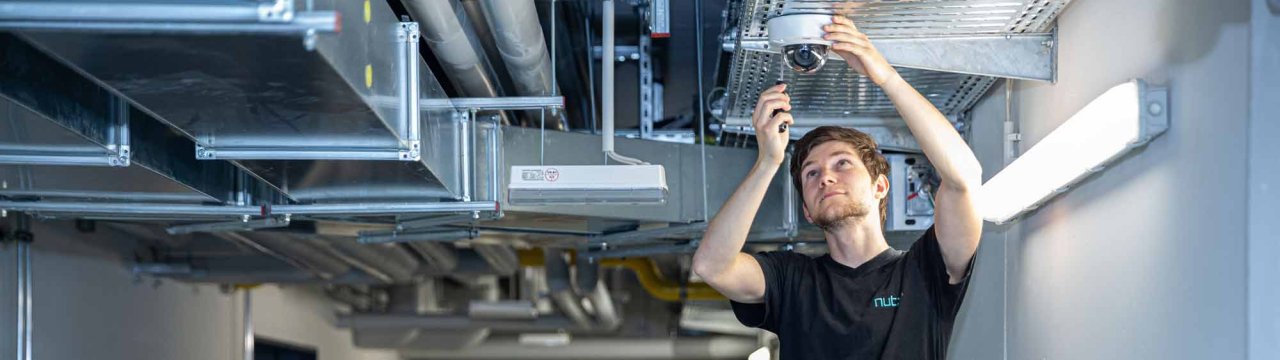 Nutz-Mitarbeiter installiert eine Überwachungskamera - Sicherheitstechnik - Nutz GmbH
